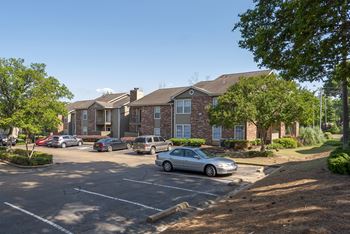 A parking lot with cars and apartment buildings in the background